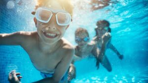 Kids swimming underwater in a clean pool - managed by Pooled